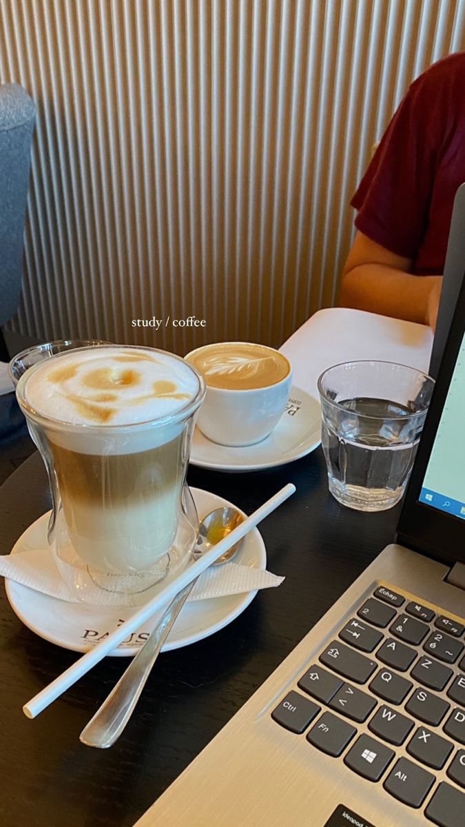 a laptop computer sitting on top of a wooden table next to a cup of coffee