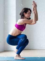 a woman doing yoga poses in front of a white brick wall with her hands up