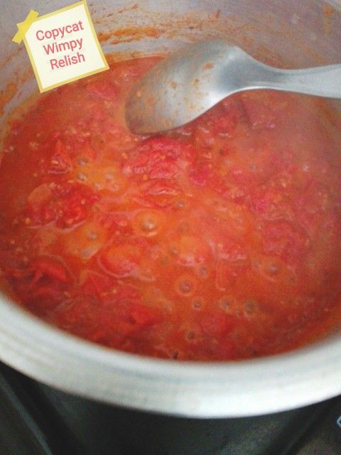 a spoon in a pot filled with red sauce