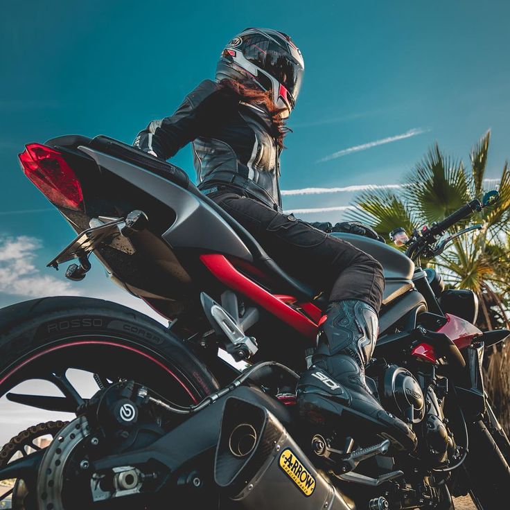 a person riding on the back of a motorcycle down a dirt road with palm trees in the background