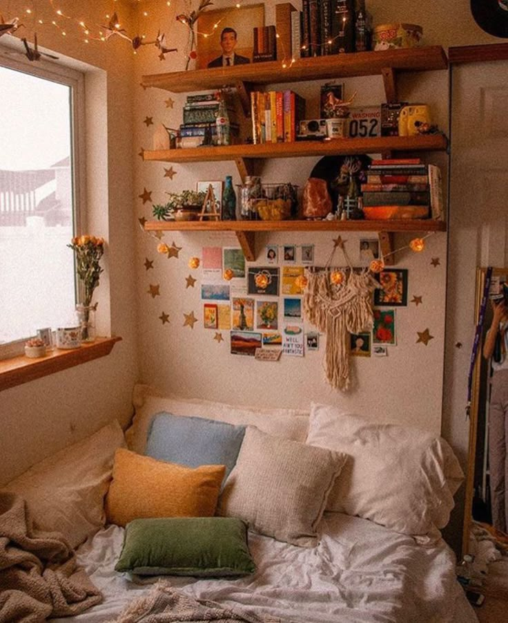 a bed with lots of pillows on top of it next to a book shelf filled with books