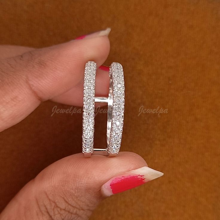 a woman's hand holding two wedding rings on her finger with red nail polish