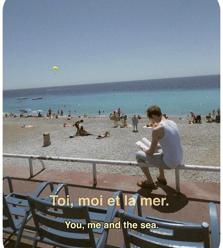 a man sitting on top of a bench next to the ocean with a quote above it