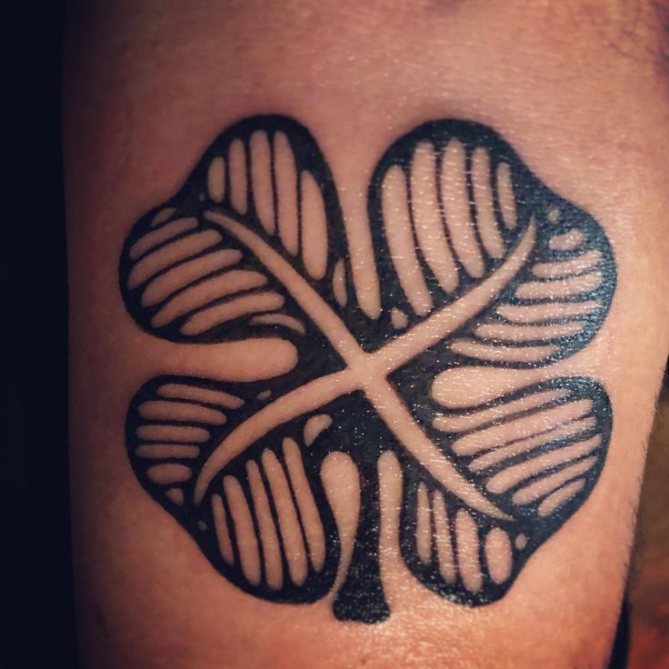 a four leaf clover tattoo on the left calf area, with an x at the center