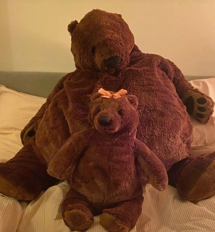 two large brown teddy bears sitting on top of a bed