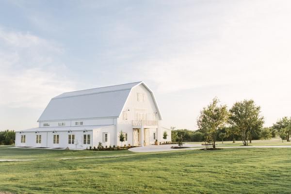 a large white barn sitting on top of a lush green field