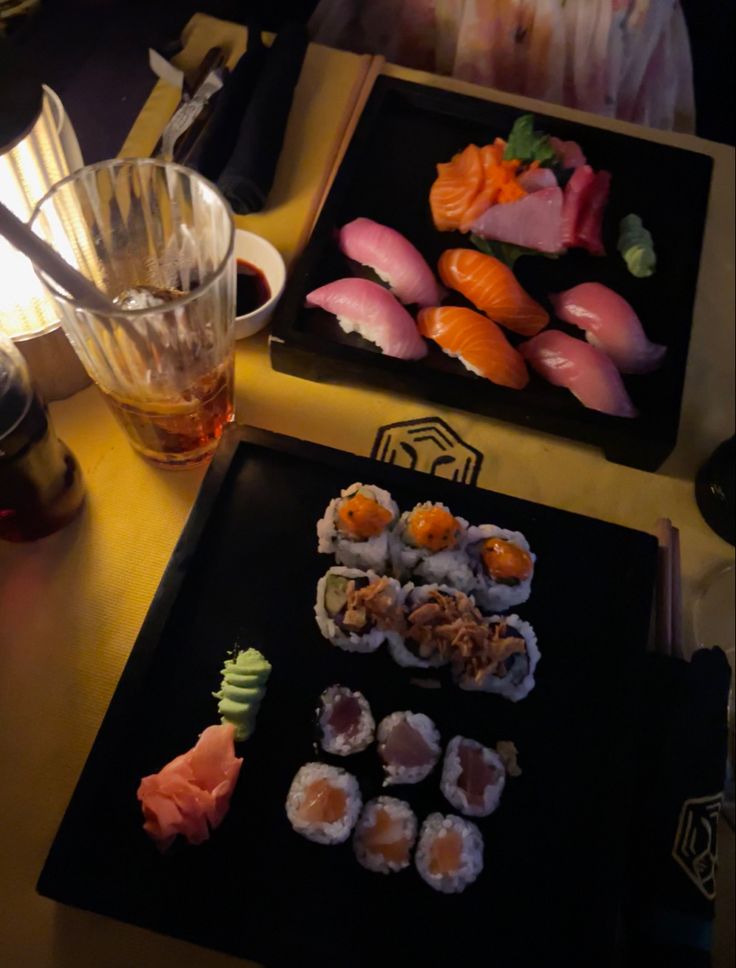 sushi is served on black plates with chopsticks in front of the plate