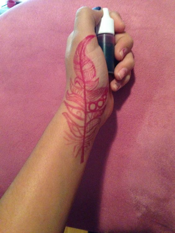 a woman's arm with a tattoo on it and a pen in her hand