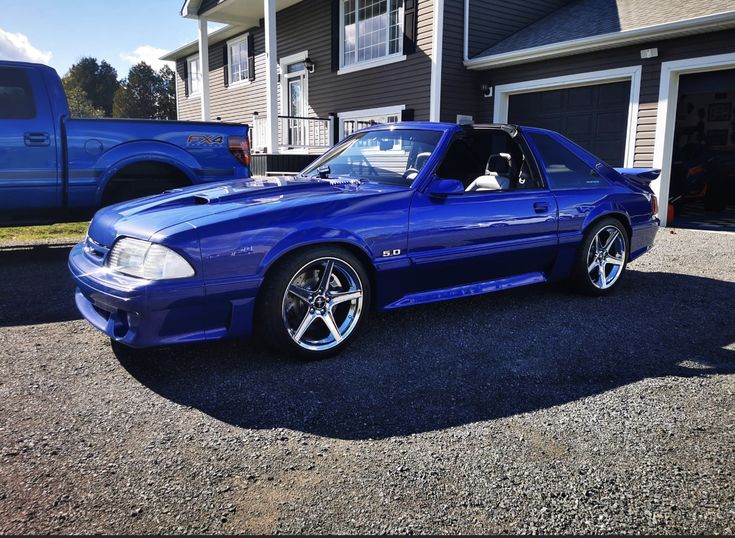 a blue sports car parked in front of a house