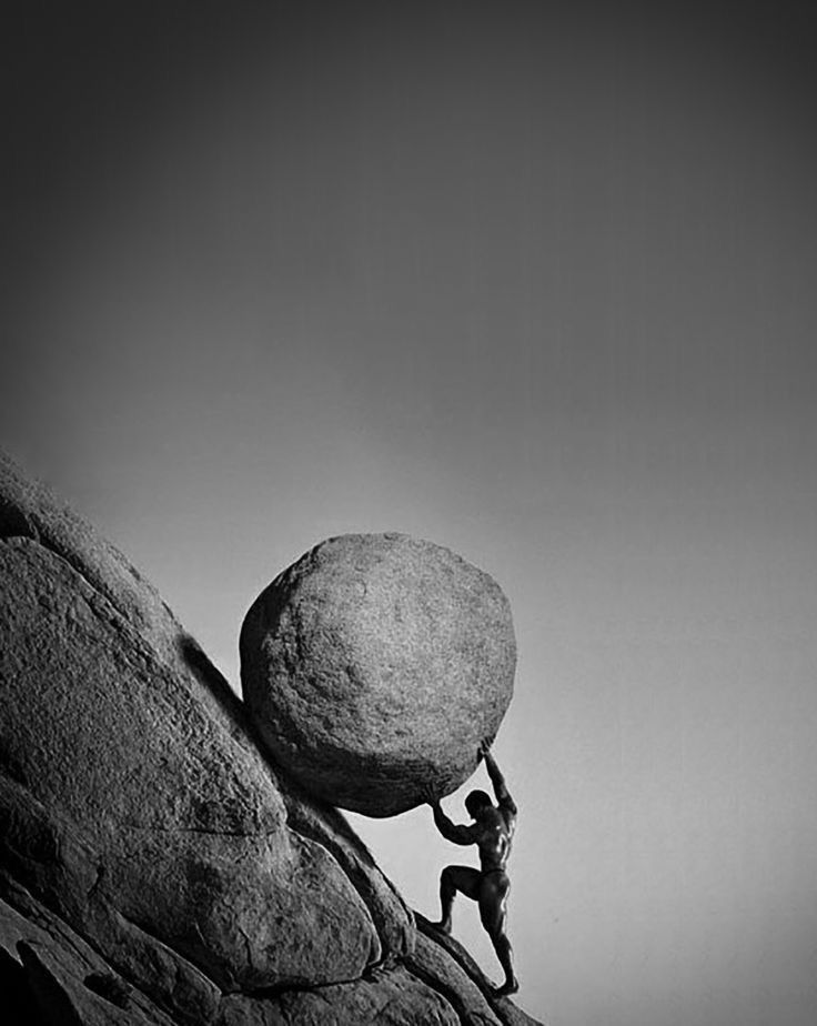 a man pushing a large rock up the side of a mountain with his hands in the air