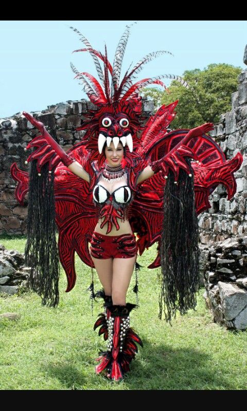 a woman in red and black costume standing on grass