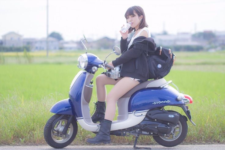 a woman is sitting on a scooter drinking from a cup