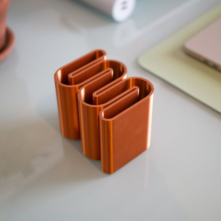 there are three orange cups on the table next to a computer mouse and pen holder