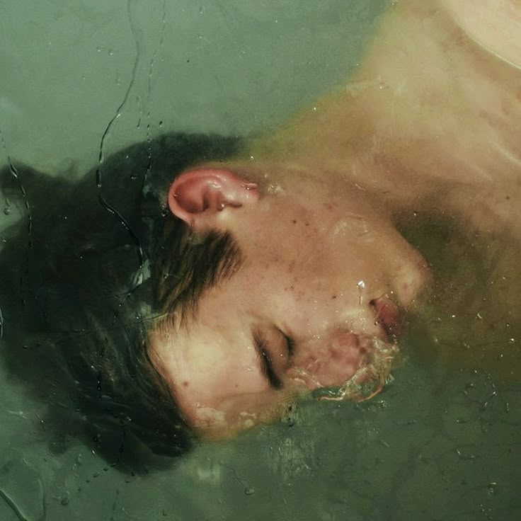 a young man swimming in the water with his head above the water's surface