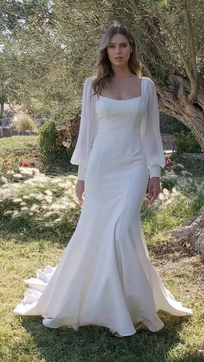 a woman in a white wedding dress standing on grass