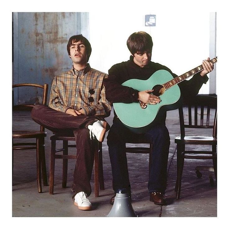 two men sitting on chairs with guitars in their hands