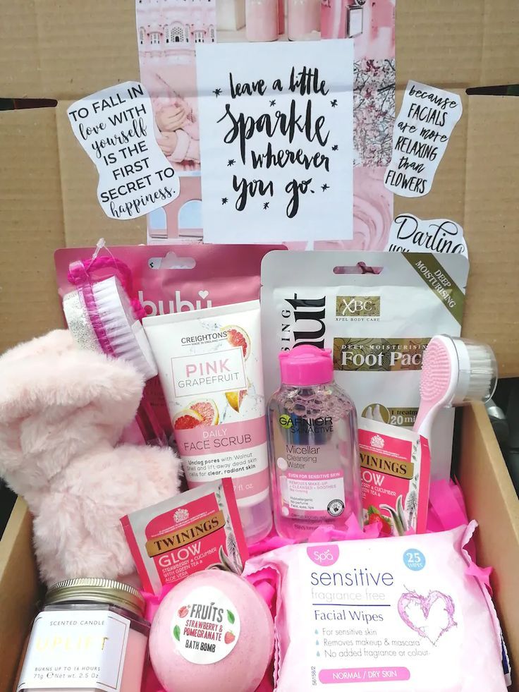 a pink teddy bear sitting in a box filled with personal care items