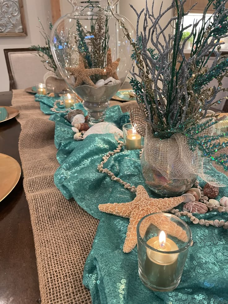 the table is set with candles, seashells and starfish in glass vases