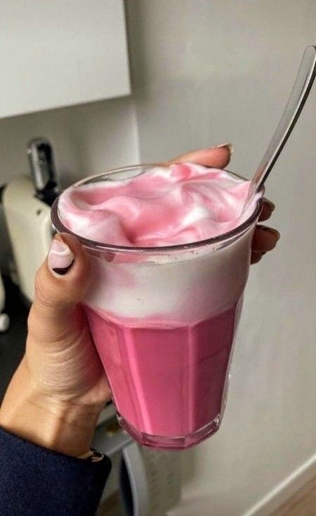 a person holding a drink with pink liquid in it