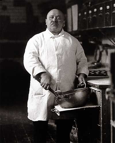 a man in a chef's coat is holding a pan