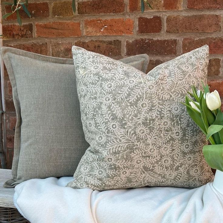 a vase with tulips sitting on top of a bed next to two pillows