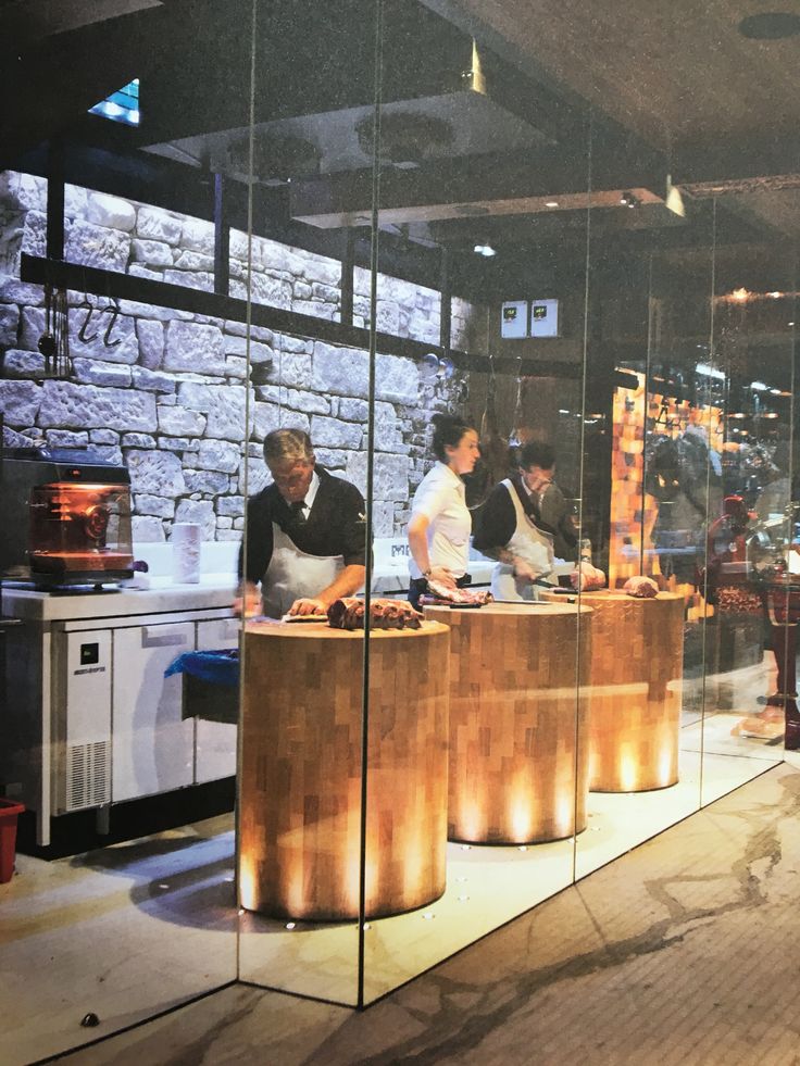 people are cooking in a restaurant with glass walls