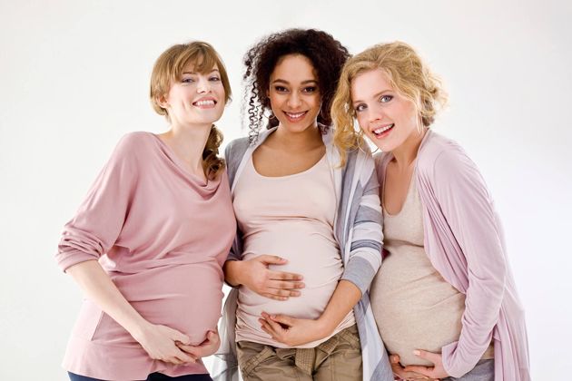 three pregnant women standing next to each other