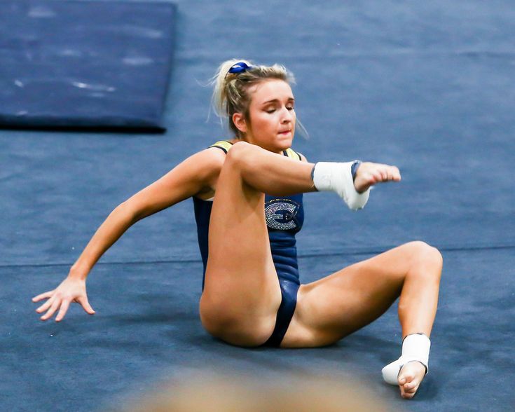 a woman is sitting on the ground with her leg up and one hand in the air