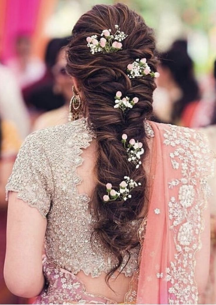 a woman in a bridal gown with flowers in her hair and another woman standing behind her