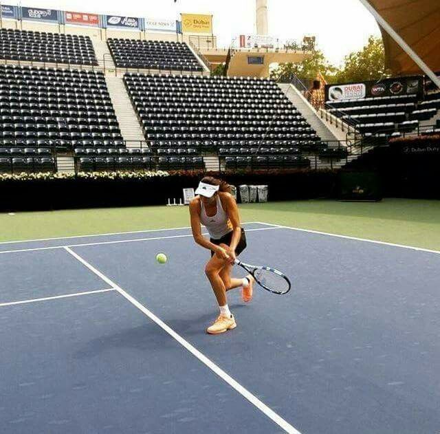 a woman is playing tennis on a court with empty bleachers in the background