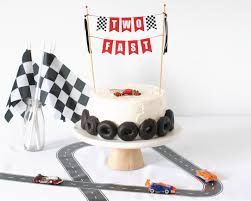 a birthday cake with cars on it and race track decorations next to it, including a checkered flag