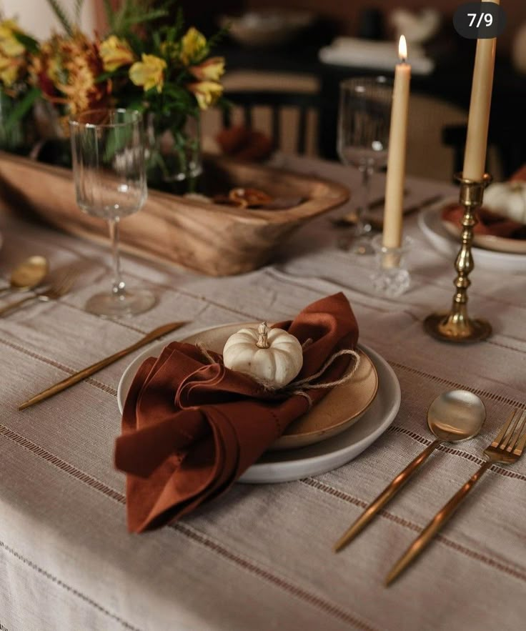 the table is set with silverware and pumpkins