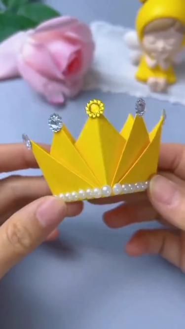 a hand holding a yellow paper crown