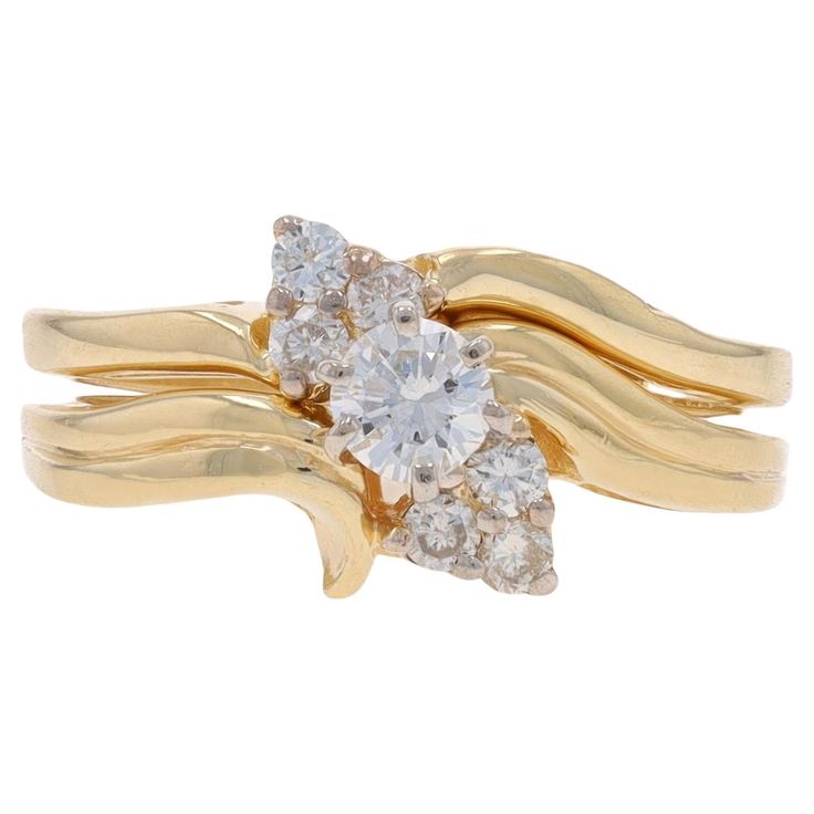 a yellow gold ring with three diamonds on the top and two leaves on the bottom