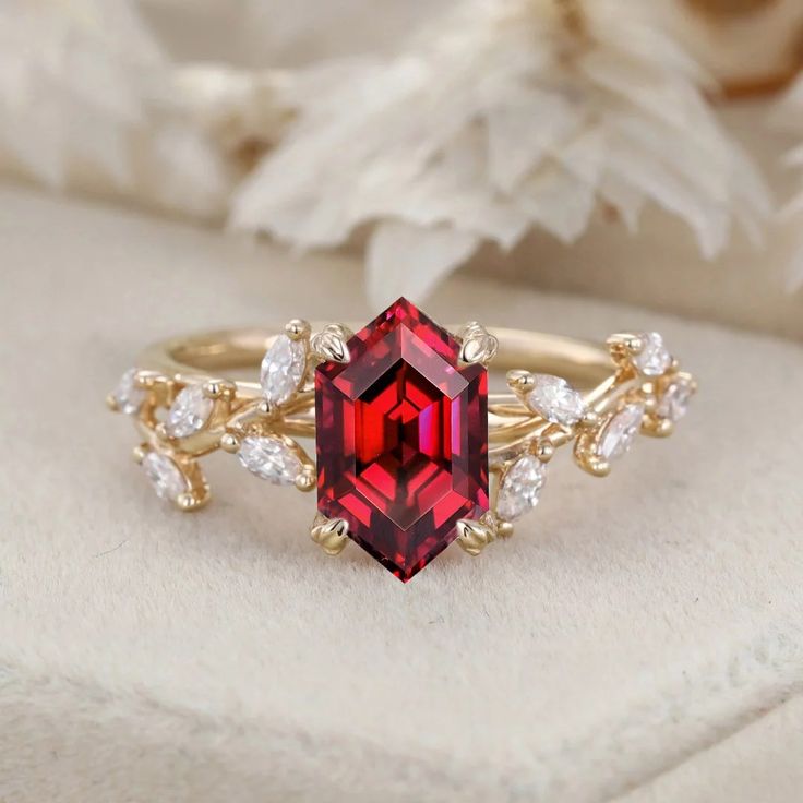 a ring with a red stone surrounded by white and yellow diamonds on top of it