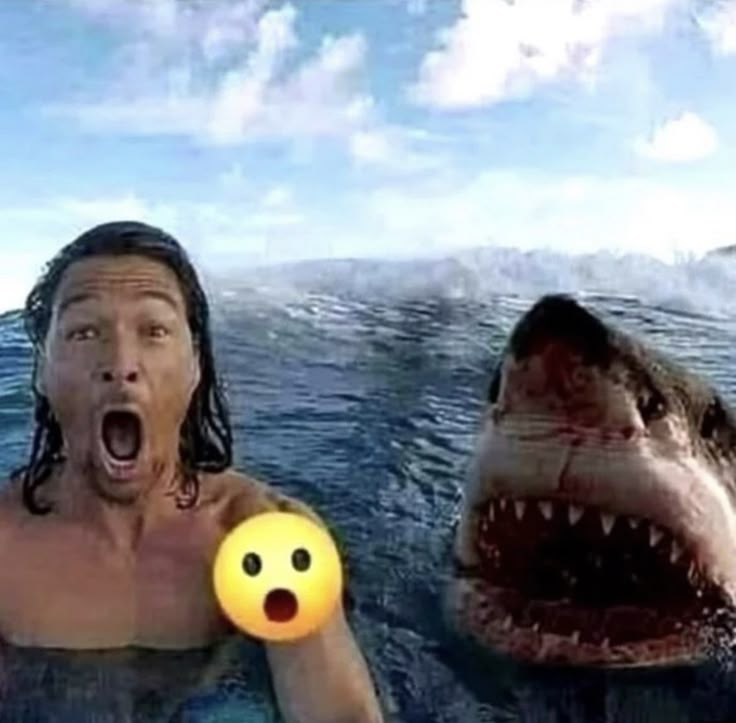 a man in the water with his mouth open next to a shark