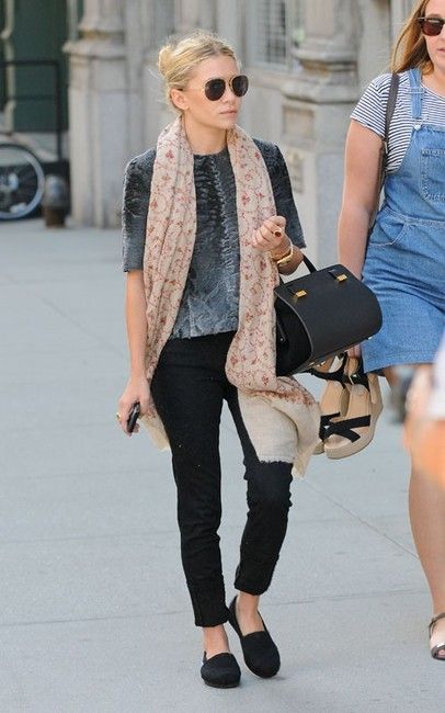 two women walking down the street with one carrying a bag and another carrying a purse