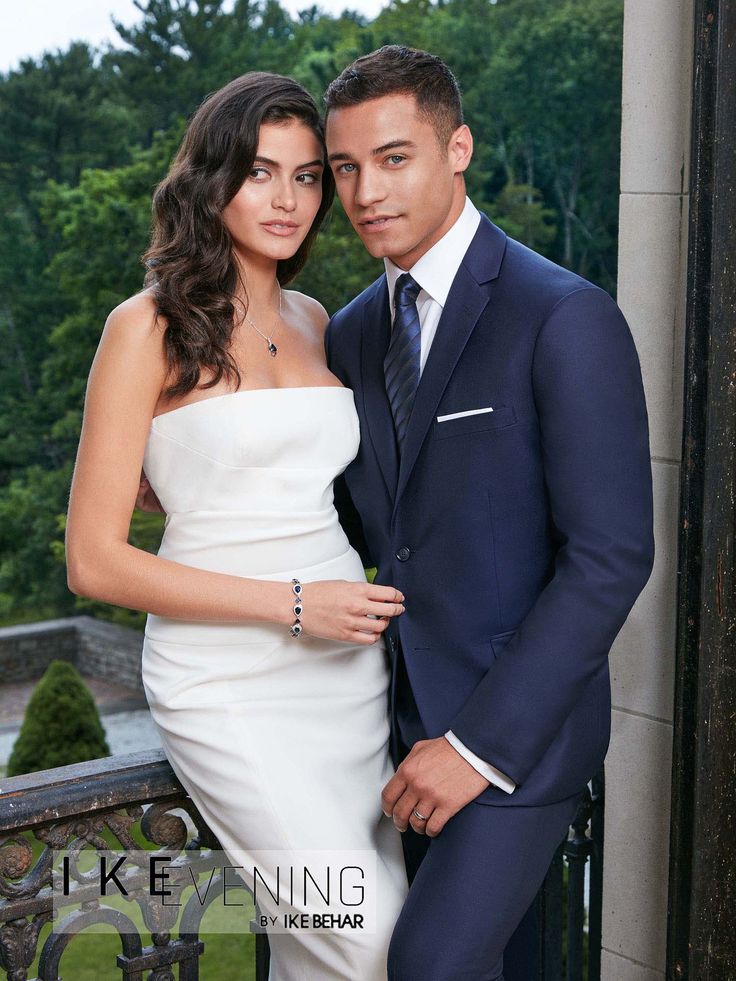 a man in a suit and woman in a white dress posing for a photo together