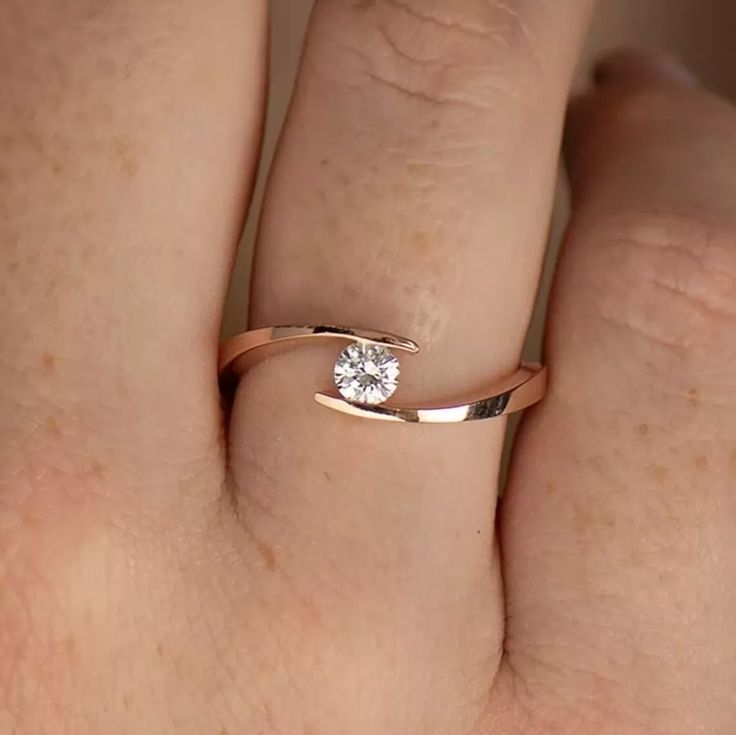 a woman's hand with a diamond ring on top of her finger, showing the side view