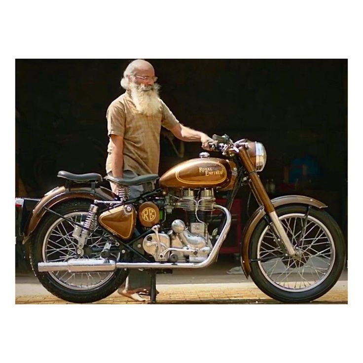 an old man standing next to a motorcycle with a long white beard and wearing glasses