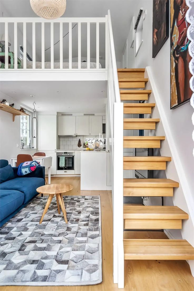 a living room filled with furniture and a stair case next to a blue couch on top of a rug