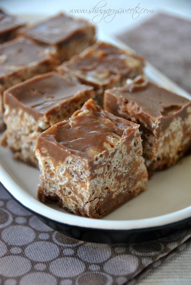 several pieces of chocolate peanut butter bars on a white plate with a brown table cloth