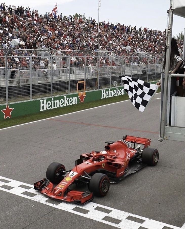 a red race car is on the track in front of an audience