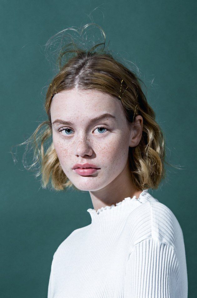 a young woman with freckled hair is posing for a photo in front of a green background