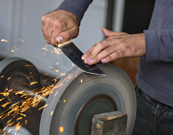 a man using a grinder on a wheel with sparks coming out of it's blades