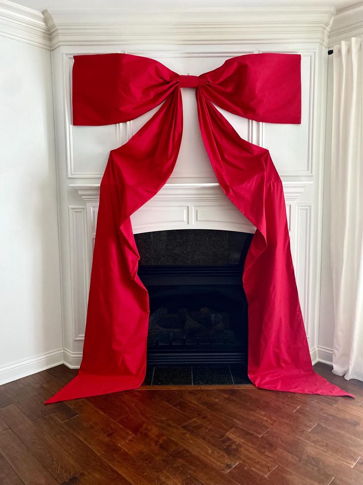 a red curtain draped over a fireplace in a room with wood floors and white walls