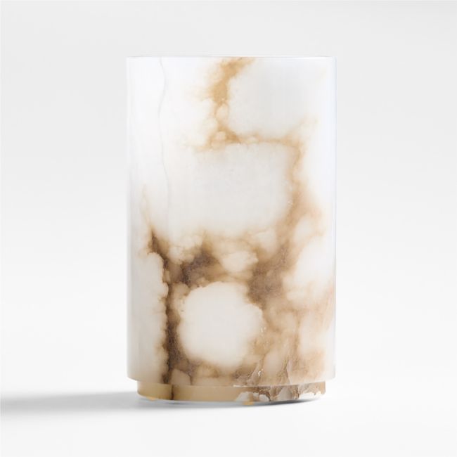 a white and brown marble vase sitting on top of a table next to a wall