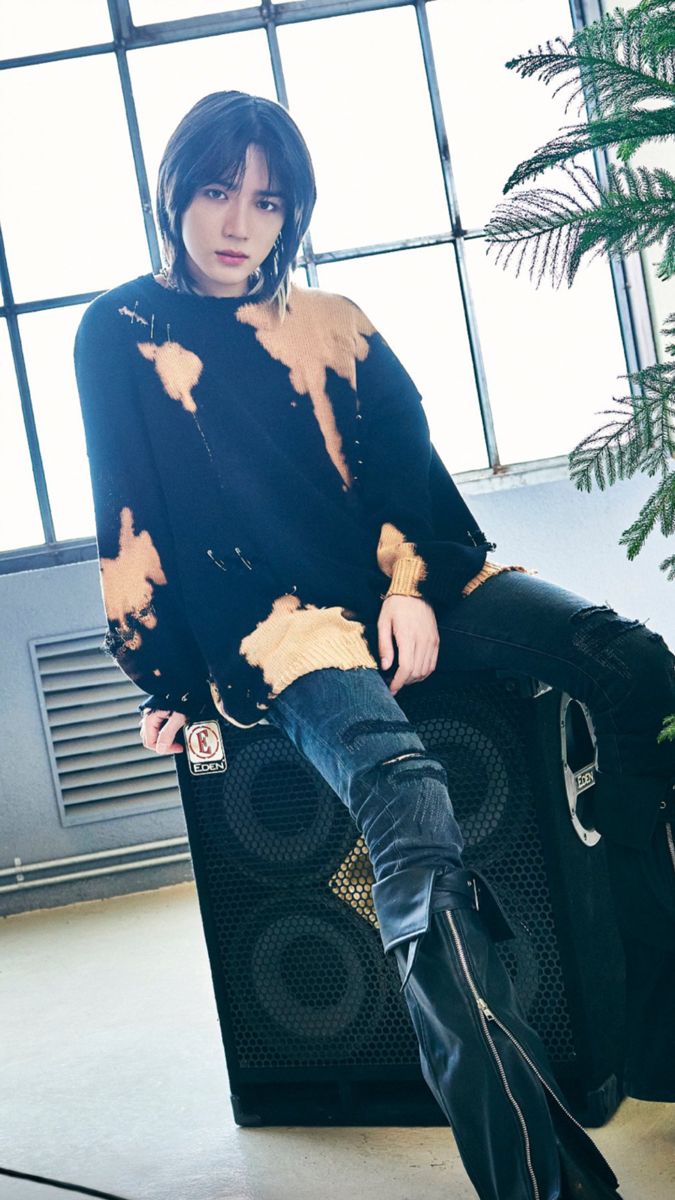 a woman sitting on top of a piece of luggage in front of a window with her legs crossed