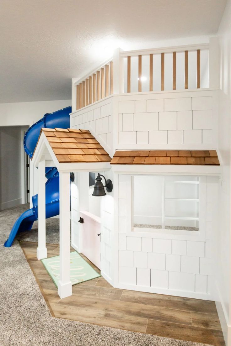 a room with white walls and a blue slide in the corner next to it is an indoor play area