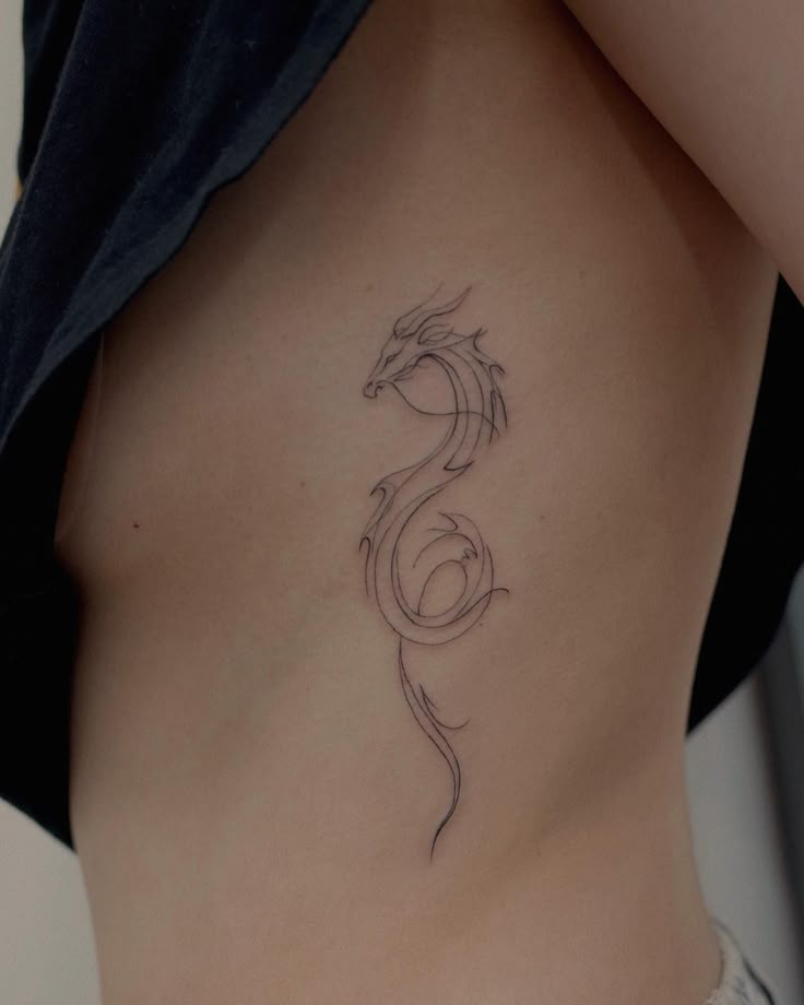 a woman's stomach with a tattoo design on the side and an outline of a dragon